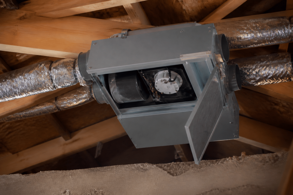 Caisson VMC gris installé sous toiture avec trappe accès ouverte