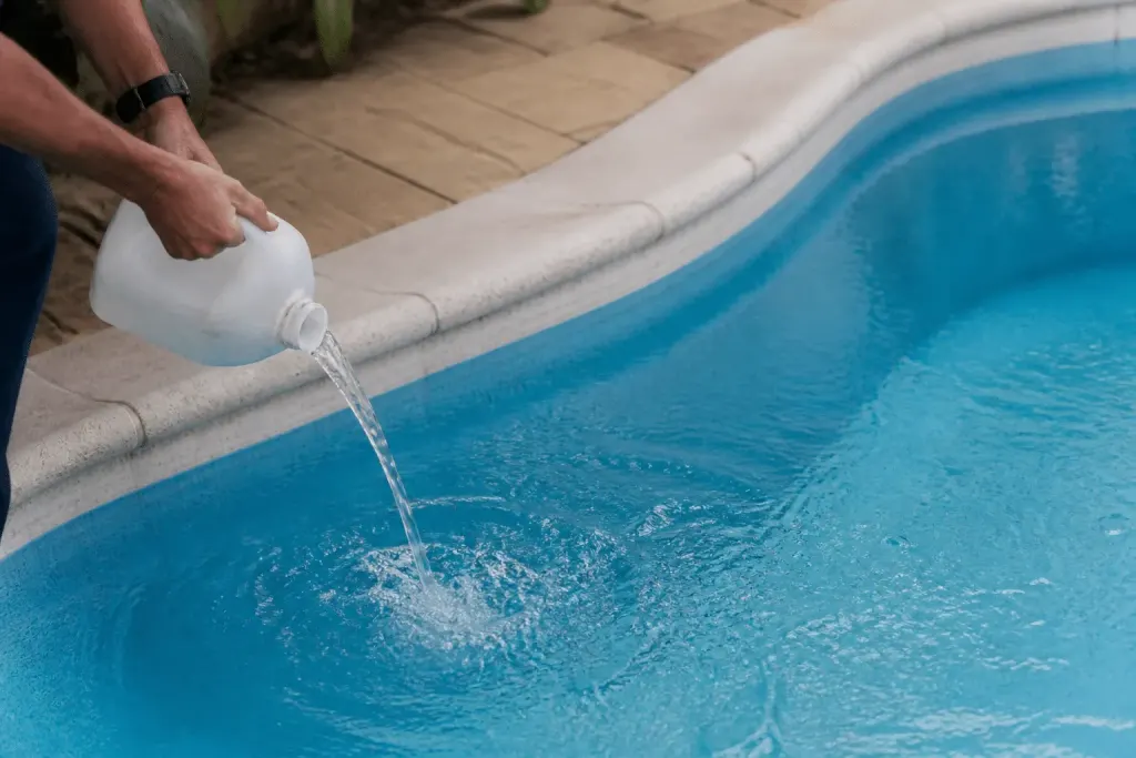 Bouteille produit chimique versée dans piscine bleu cristallin