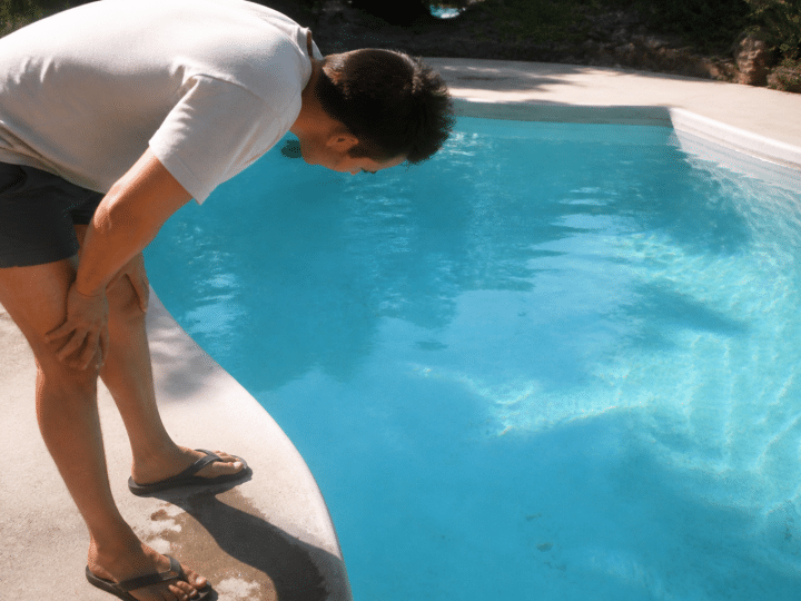 Homme penche inspectant le fond bleu piscine
