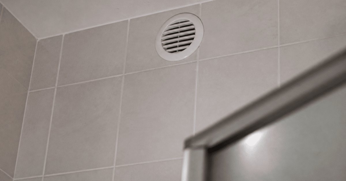 Grille d'aeration blanche installee en haut du mur carrelage