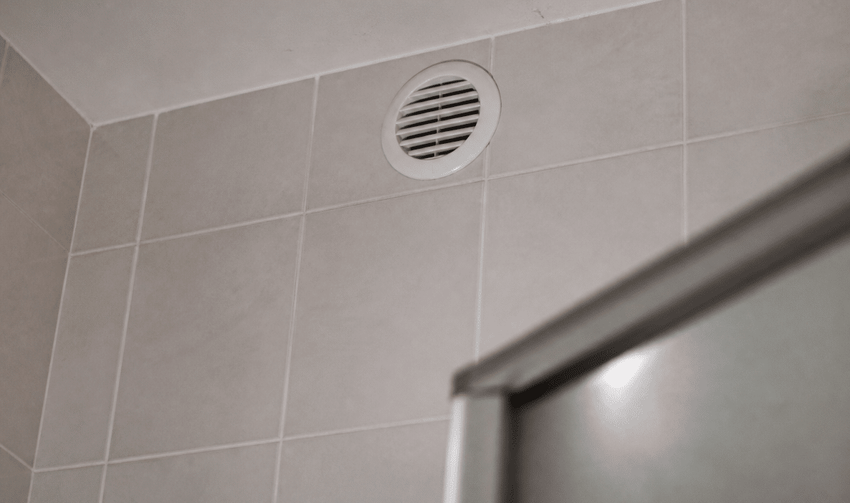 Grille d'aeration blanche installee en haut du mur carrelage
