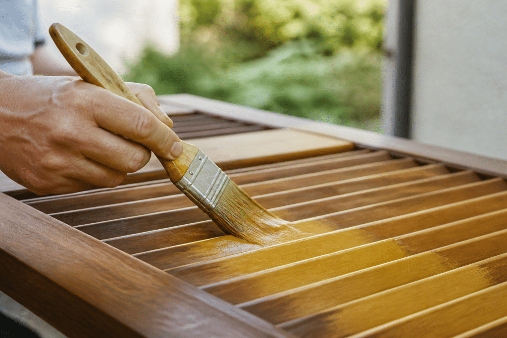 Pinceau appliquant lasure dorée sur bois de volet
