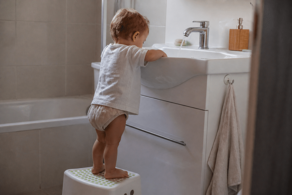 Jeune enfant debout devant lavabo blanc avec marchepied
