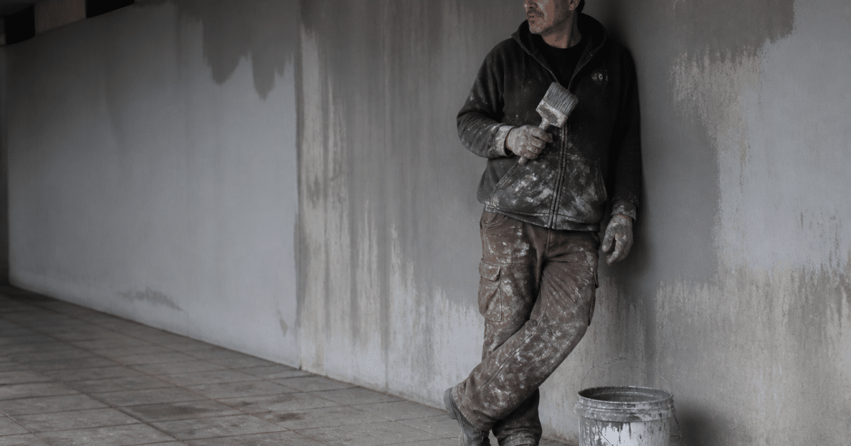 Personne appuyee contre mur souterrain avec pinceau et seau de peinture