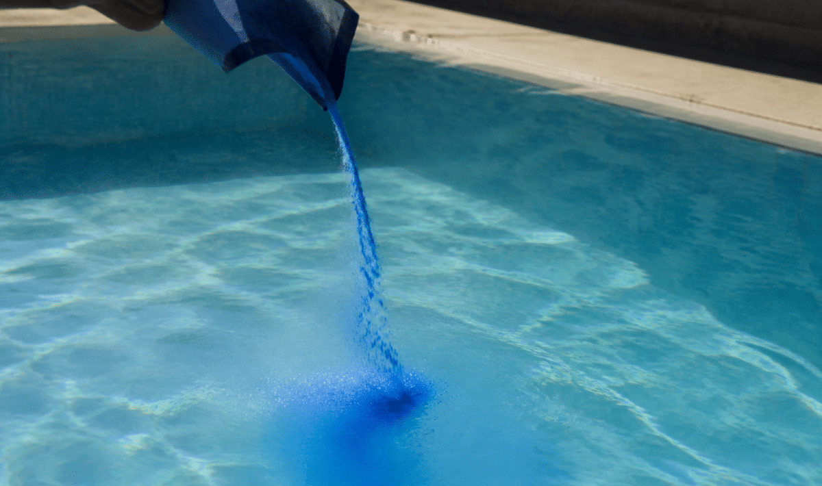 Poudre bleue versee dans eau piscine cristalline