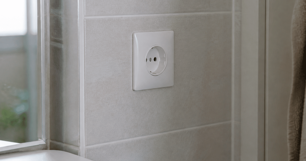 Prise electrique blanche installee verticalement sur carrelage salle bain