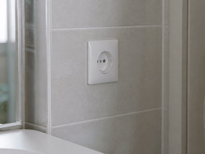 Prise electrique blanche installee verticalement sur carrelage salle bain
