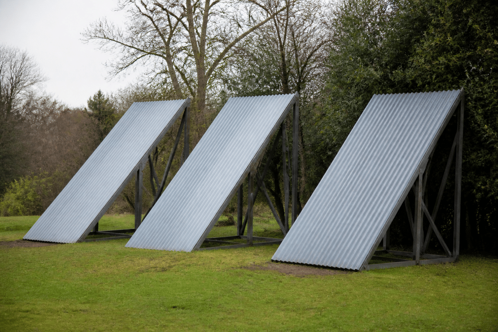 Trois structures metalliques inclinées avec toles ondulees grises