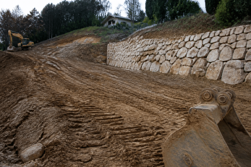 Terrain pentu avec engins de terrassement et mur de soutènement