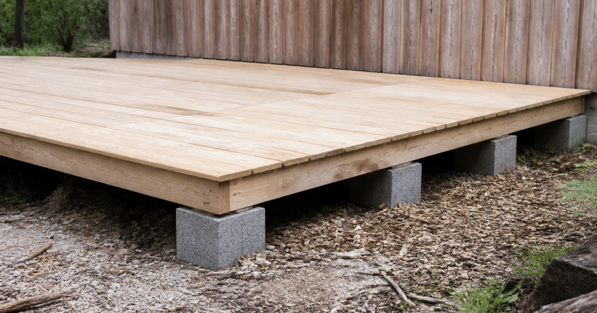 Plateforme surélevée en bois reposant sur plots de béton gris