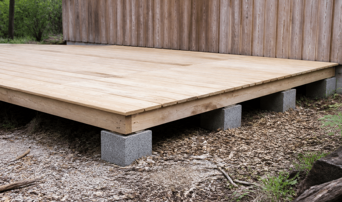 Plateforme surélevée en bois reposant sur plots de béton gris