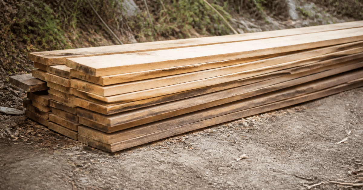 Planches bois empilees horizontalement posees directement sur sol