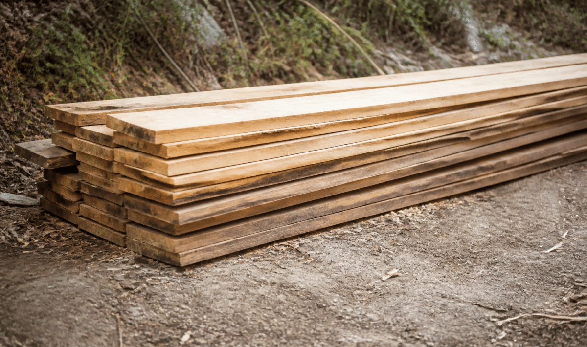 Planches bois empilees horizontalement posees directement sur sol