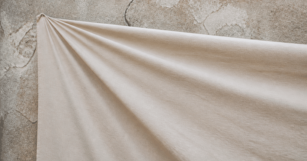 Grand tissu beige tendu devant mur fissure