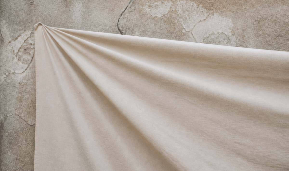 Grand tissu beige tendu devant mur fissure